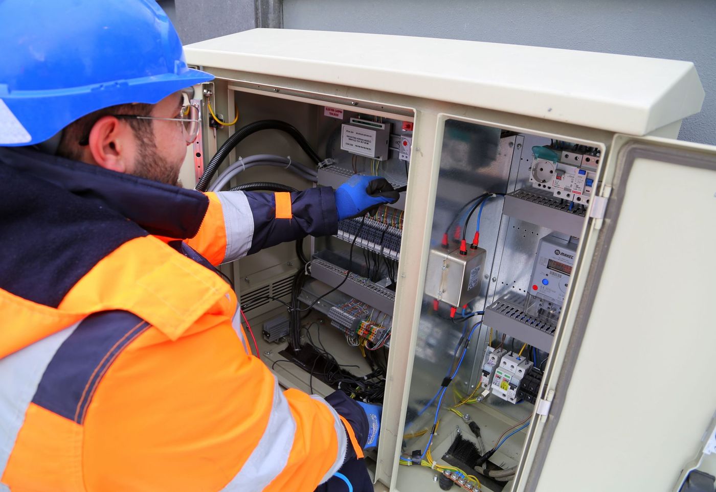 Technician working inside a controls cabinet